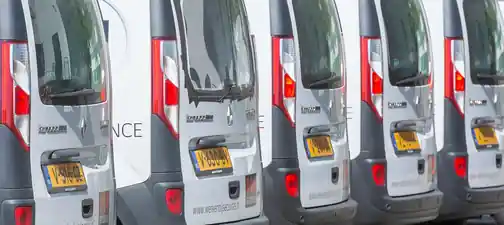 Sıra hâlinde park etmiş beyaz şirket araçlarından oluşan filo